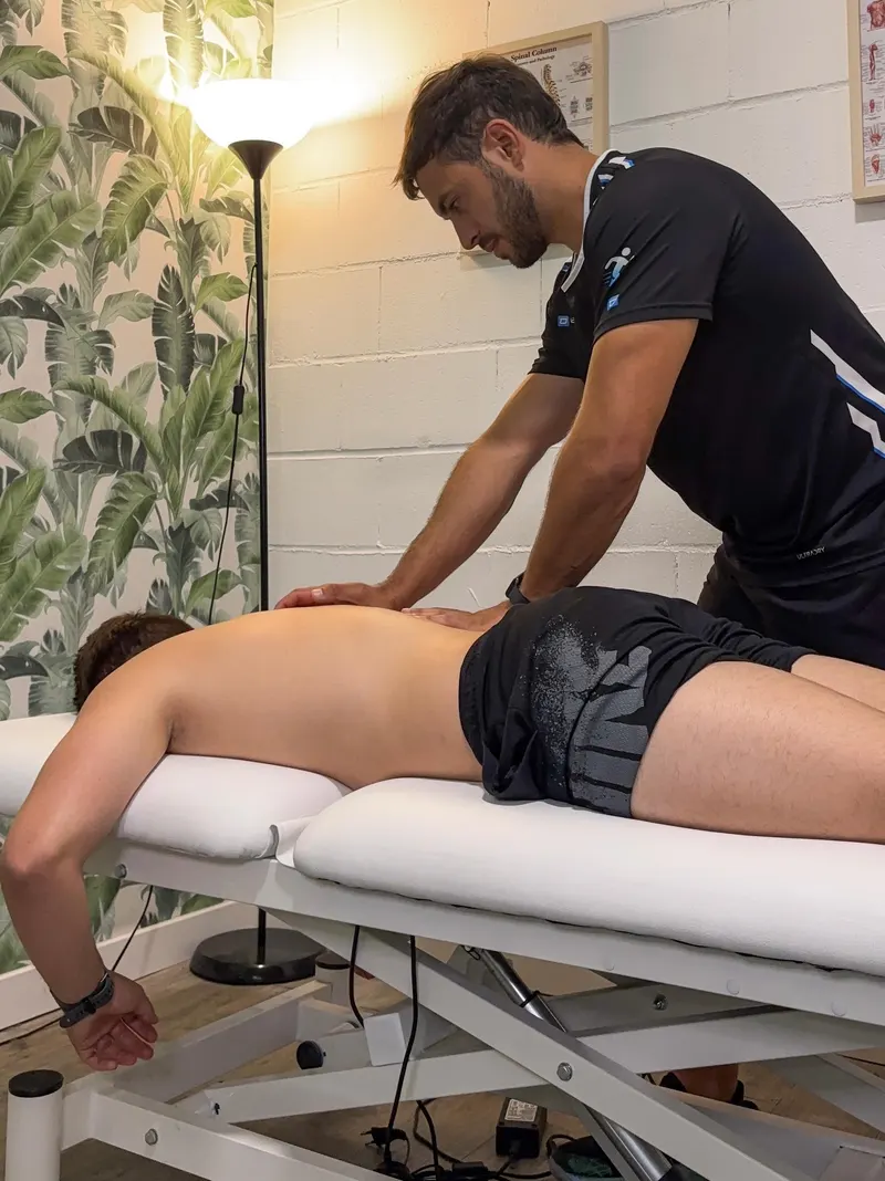 Alex aplicando terapia manual en la espalda de un paciente en su consulta de Colmenar Viejo